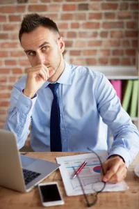 Thoughtful businessman at desk with laptop