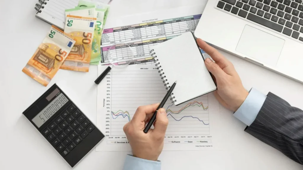man with pen spiral notebook and bank notes