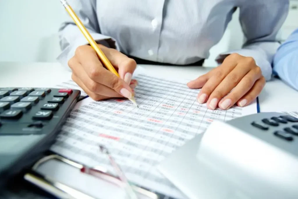 lady working on printed spreadsheet with a pencil